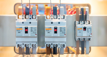 Close-up of three industrial circuit breakers in a row on an electrical panel, labeled 250, 150, and 100 amps.