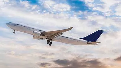 White passenger jet with a navy blue tail taking off into a cloudy sky, landing gear extended.