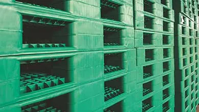 Stacked rows of green plastic pallets in an angled close-up.