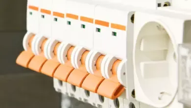 Close-up of electrical circuit breakers with orange switches in a panel